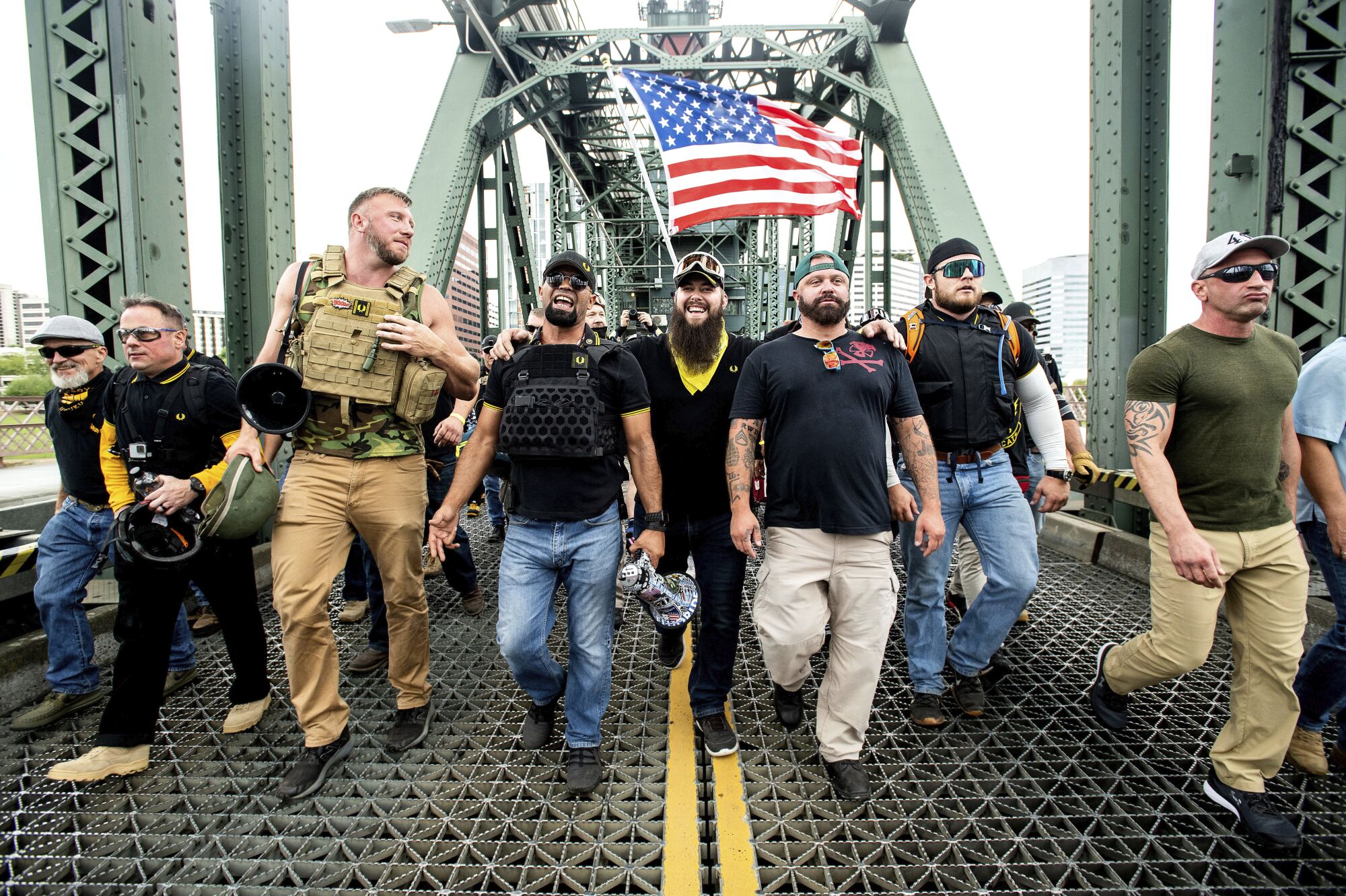 Men in tactical vests walk across a bridge