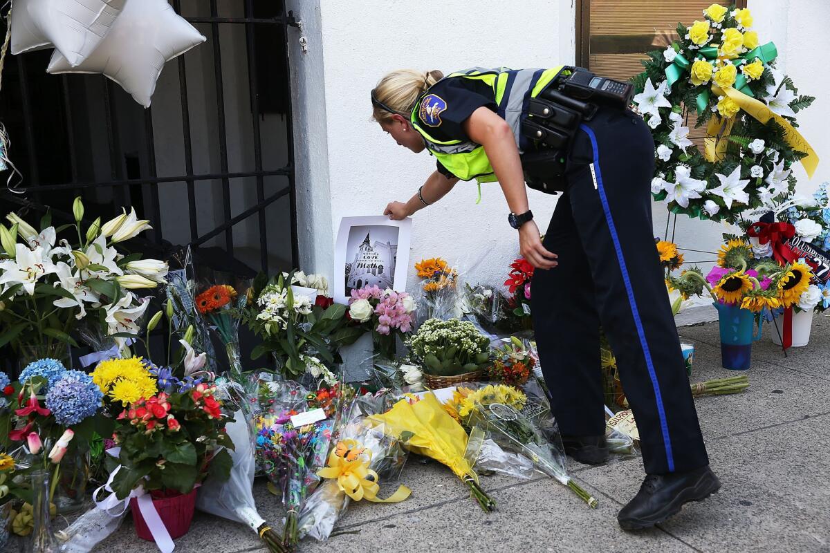 A Charleston police officer rearranges an item on the memorial in front of Emanuel AME Church Thursday after a mass shooting at the church that killed nine people.