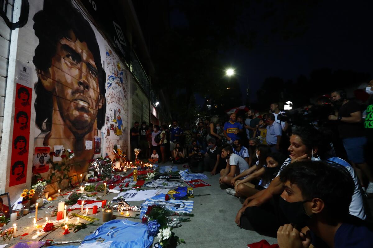 Hinchas acongojados frente a un afiche de Diego Maradona  
