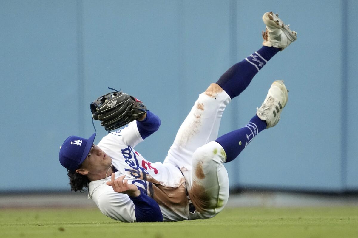 Dodgers center fielder James Outman rolls after making a diving catch.