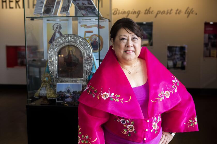 Chula Vista, CA - September 29: Anamaria Cabato, executive director of PASACAT, the Philippine performing arts company, and co-chair of the "Filipinos of South Bay" exhibition committee, poses for a photo inside the exhibit at the Civic Center Library Chula Vista on Thursday, Sept. 29, 2022 in Chula Vista, CA. The exhibit includes local stories, photos, and other memorabilia highlighting the history of Filipinos in the South Bay during Filipino American History Month in October. (Meg McLaughlin / The San Diego Union-Tribune)
