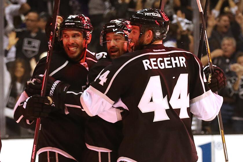 Kings forward Justin Williams, center, is congratulated by teammates Dwight King, left, and Robyn Regehr after scoring the go-ahead goal during the third period of the Kings' 4-1 win over the San Jose Sharks in Game 6 of the Western Conference quarterfinals at Staples Center.