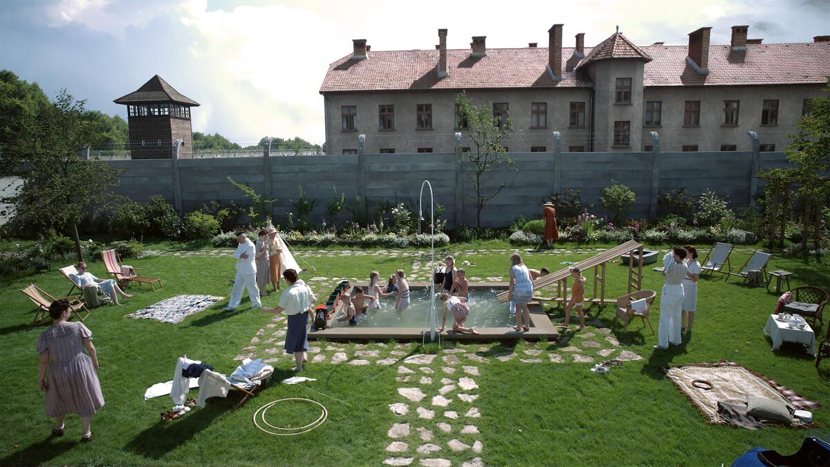 A concentration camp looms behind a family's garden.