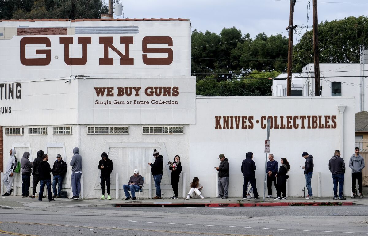 People stand in line outside a gun store