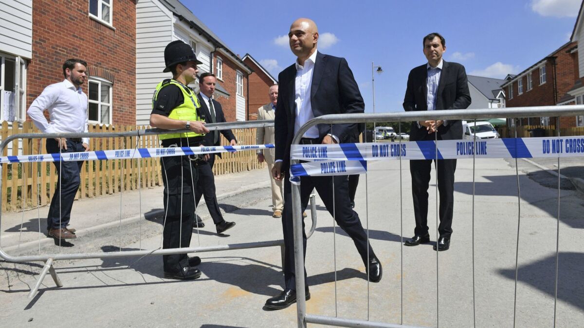 Britain's Home Secretary Sajid Javid, center, exits the police cordon at Muggleton Road where counter-terrorism officers are investigating a couple's exposure to the nerve agent Novichok in Amesbury, England, on Sunday.