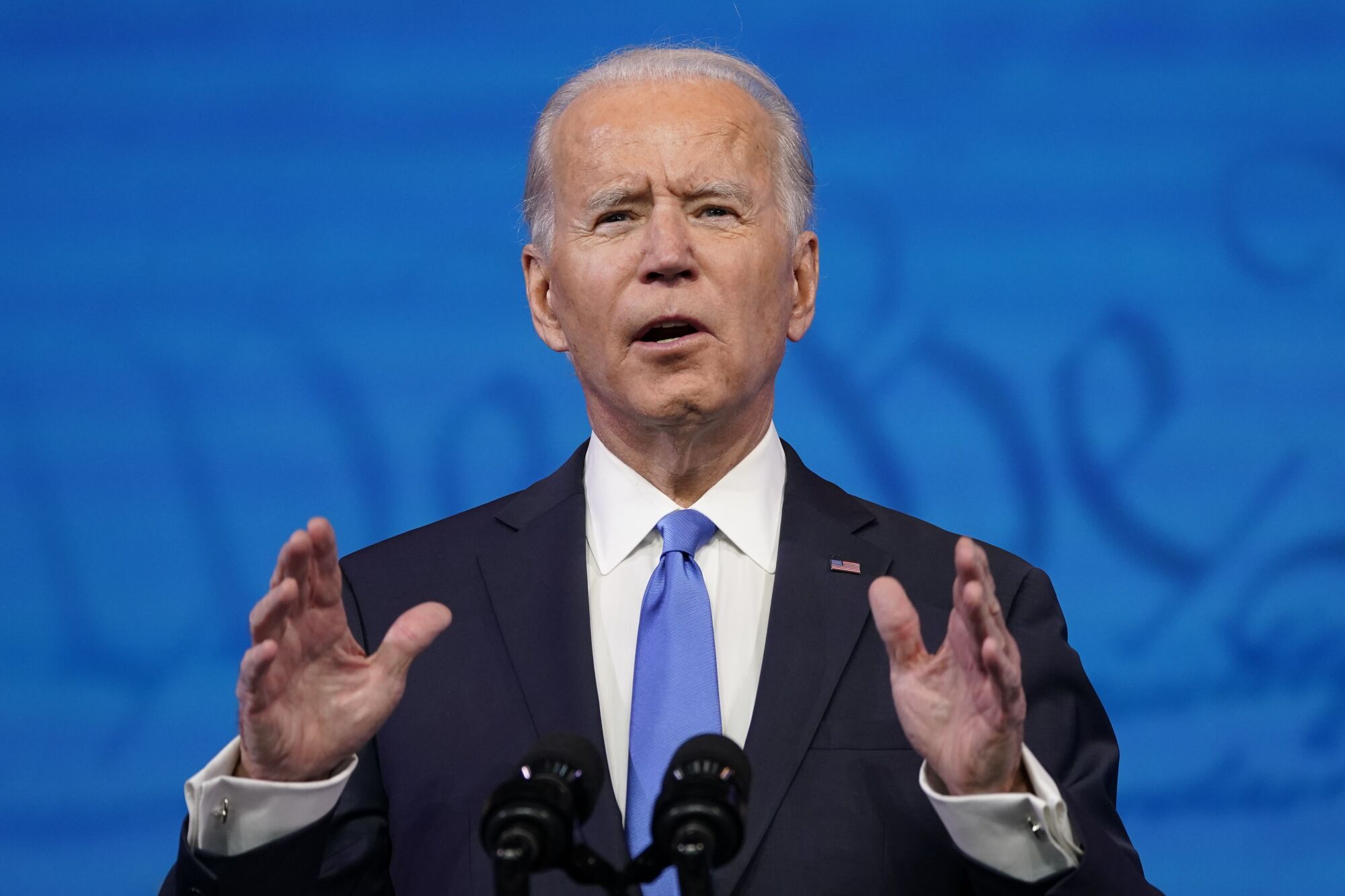 President-elect Joe Biden speaks with a blue background behind him