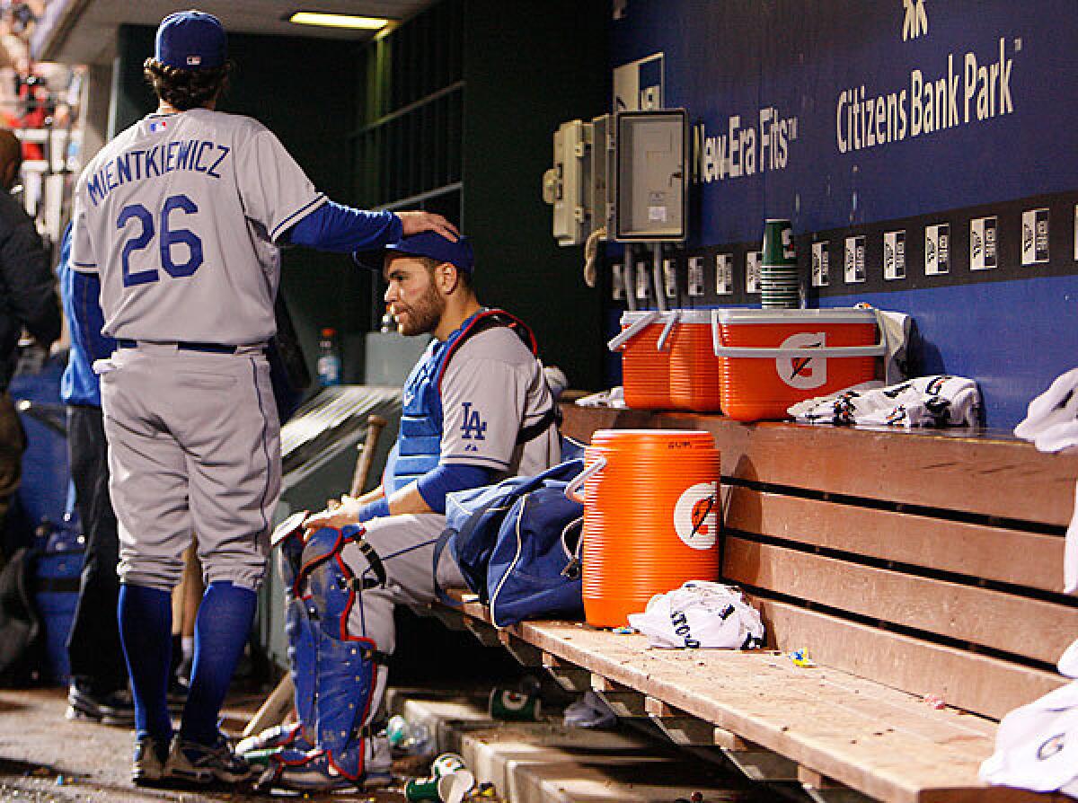 Dodgers infielder Doug Mientkiewicz consoles catcher Russell Martin, who is the last to leave the dugout Wednesday night at Citizens Bank Park after a 10-4 loss to the Phillies in Game 5 of the National League Championship Series.Philadephia won the series, 4-1.