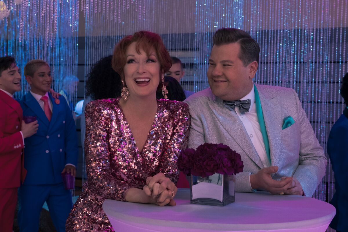 Meryl Streep wears a glittery gown and earrings and James Corden wears a glittery silver tux in a scene from "The Prom." 