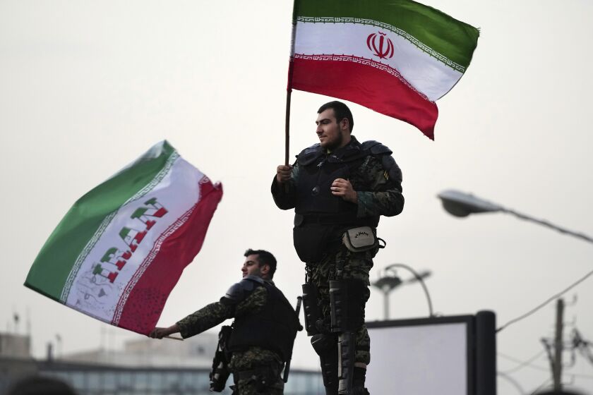 Two anti-riot police officers wave the Iranian flags during a street celebration after Iran defeated Wales in Qatar's World Cup, at Sadeghieh Sq. in Tehran, Iran, Friday, Nov. 25, 2022. Iran's political turmoil has cast a shadow over Iran's matches at the World Cup, spurring tension between those who back the team and those who accuse players of not doing enough to support the protests that started Sept. 16 over the death of a 22-year-old woman in the custody of the morality police. (AP Photo/Vahid Salemi)