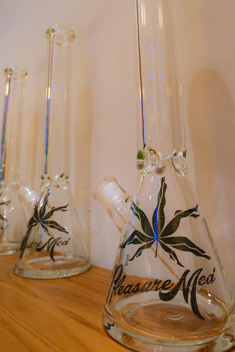 A glass waterpipe decorated with a logo and the word PleasureMed
