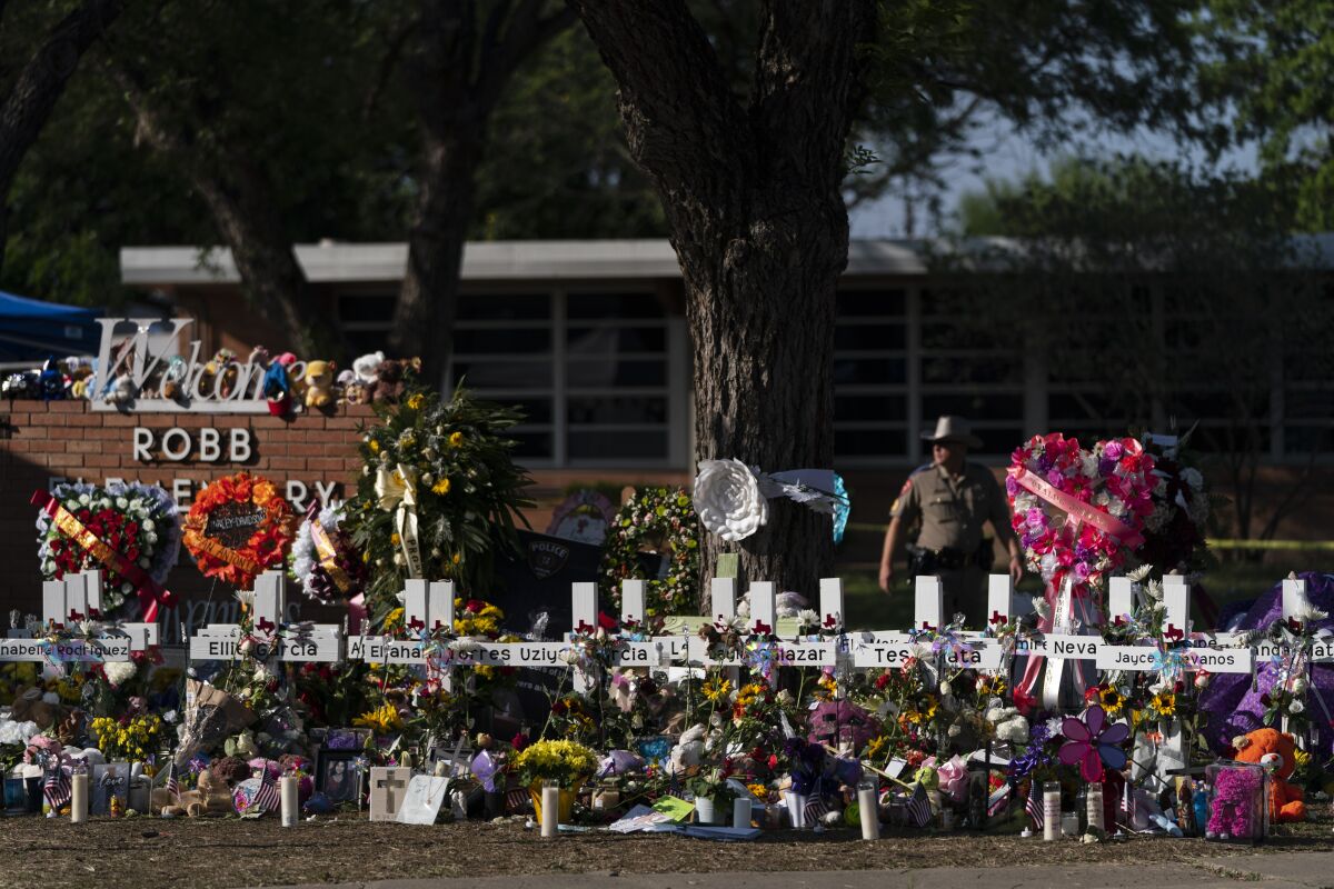 ARCHIVO - Flores y velas yacen junto a cruces frente a la Escuela Primaria Robb, en Uvalde, Texas, el 28 de mayo de 2022