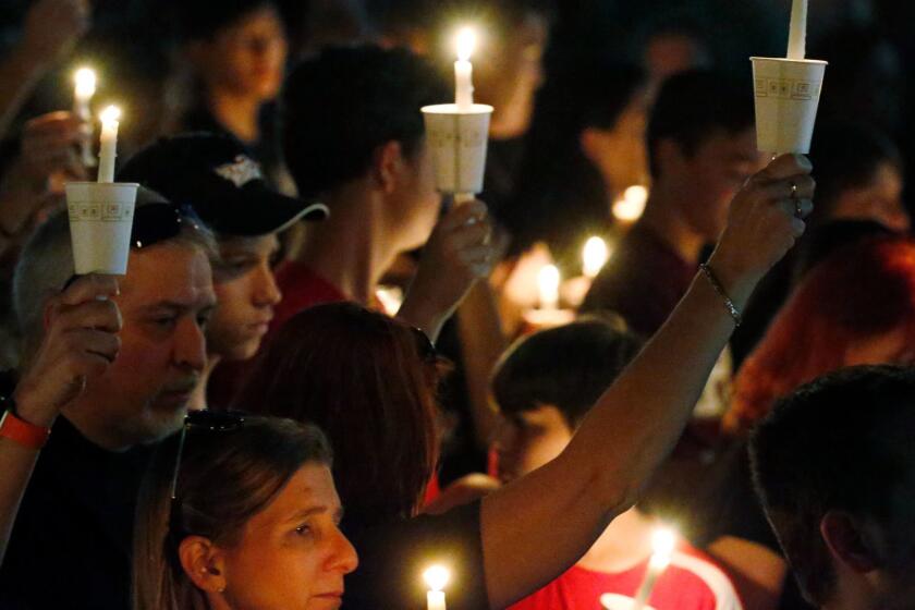 Attendees raise their candles at a candlelight vigil for the victims of the shooting at Marjory Stoneman Douglas High School, Thursday, Feb. 15, 2018, in Parkland, Fla. An orphaned 19-year-old with a troubled past and his own AR-15 rifle was charged with 17 counts of premeditated murder Thursday morning after being questioned for hours by state and federal authorities following the deadliest school shooting in the U.S. in five years. (AP Photo/Wilfredo Lee)
