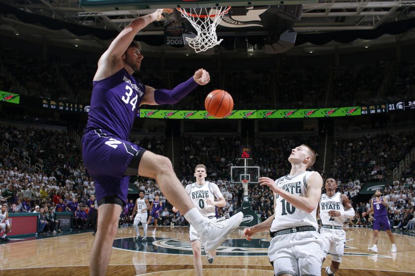 Northwestern's Matthew Nicholson, left, dunks against Michigan State's Joey Hauser (10) during the first half of an NCAA college basketball game, Sunday, Dec. 4, 2022, in East Lansing, Mich. (AP Photo/Al Goldis)