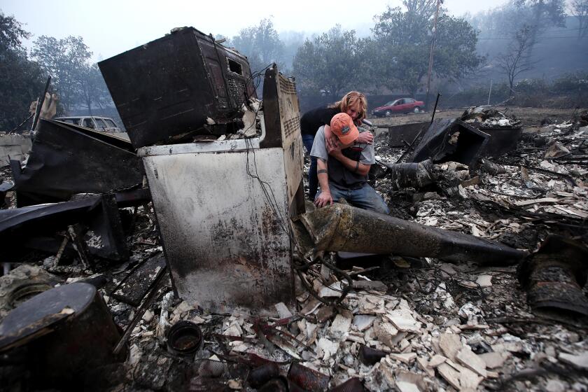 Sheri Marchetti-Perrault and James Benton embrace as they sift through the remains of their home.