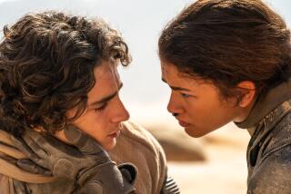 Zendaya's gloved hand caresses Timothée Chalamet's face in a scene from "Dune."