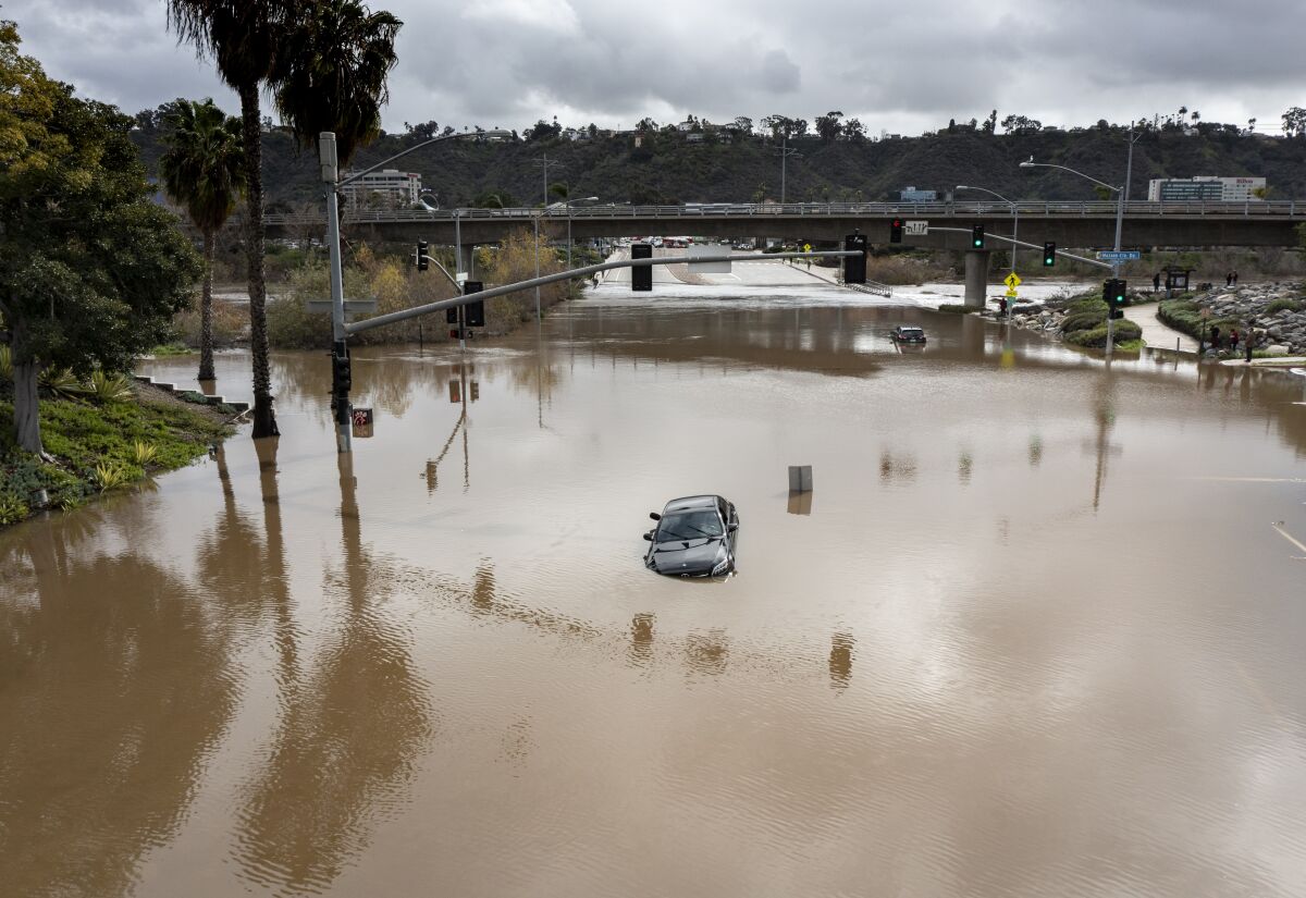 A Mercedes sits in the middle of the a flooded Mission Center Road near the San Diego River in Mission Valley 