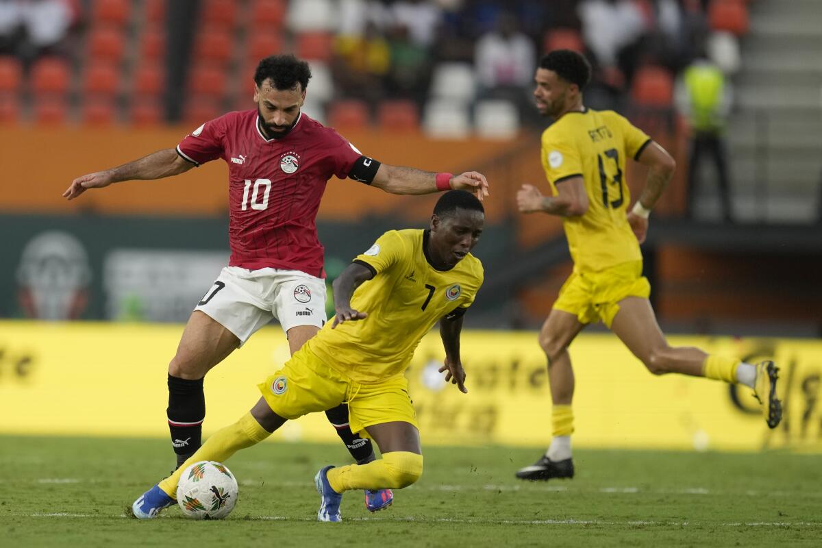 El mozambiqueño Elias Pelembe, a la derecha del egipcio Mohamed Salah