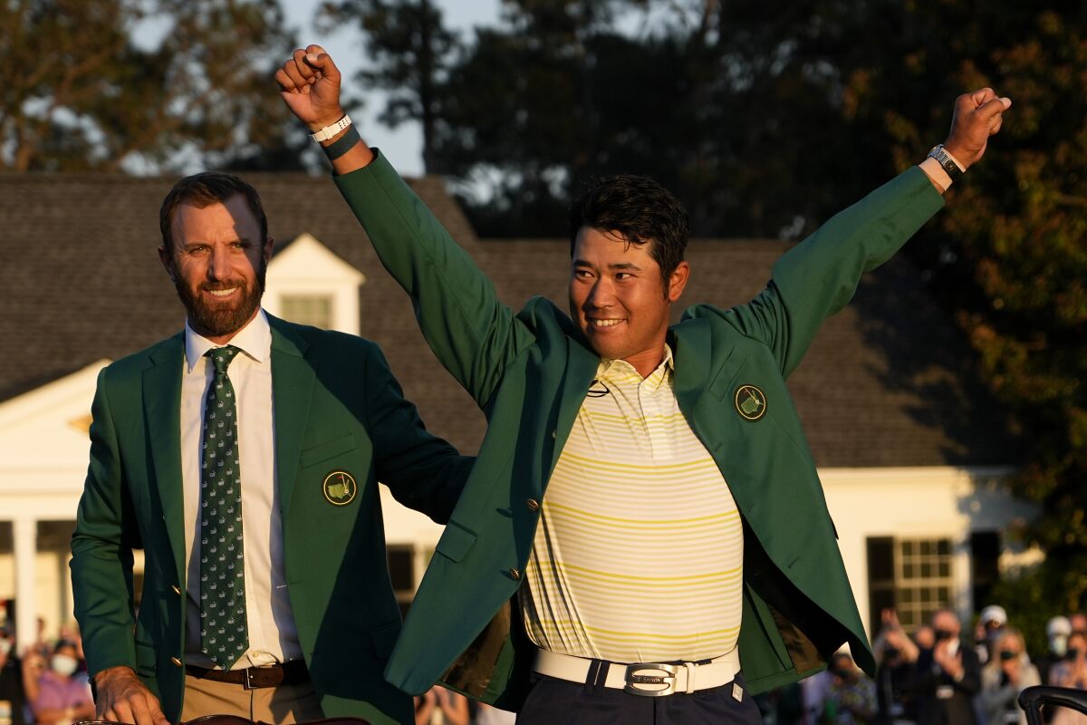 FILE - In this Sunday, April 11, 2021 file photo, Hideki Matsuyama, of Japan, puts on the champion's green jacket after winning the Masters golf tournament as Dustin Johnson watches in Augusta, Ga. Matsuyama already is thinking about what to serve at the champions dinner next April. It likely will include sushi. (AP Photo/David J. Phillip, File)