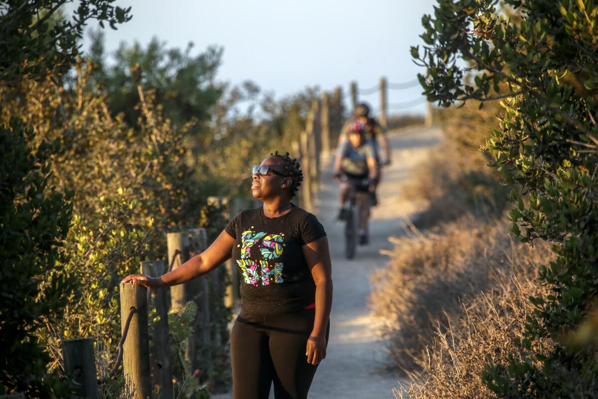 A woman on a hiking trail with two cyclists in the distance