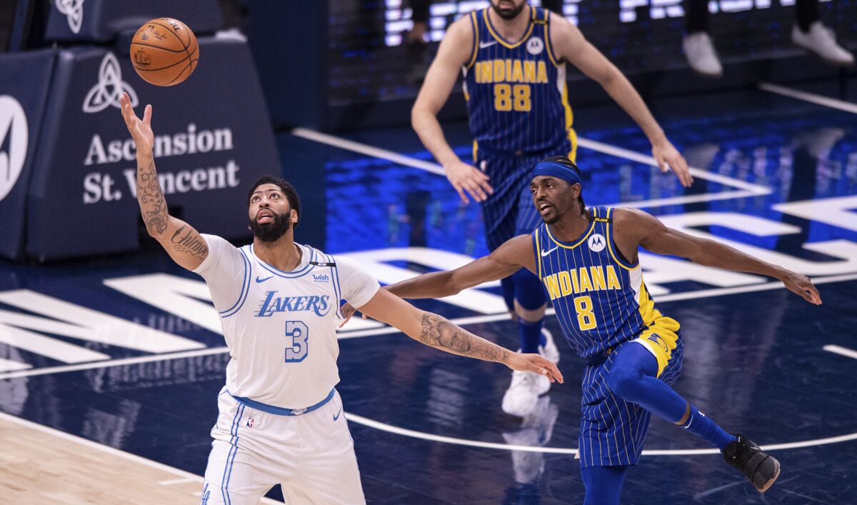 The Lakers' Anthony Davis works to regain control of the ball as the Pacers' Justin Holiday defends May 15, 2021.
