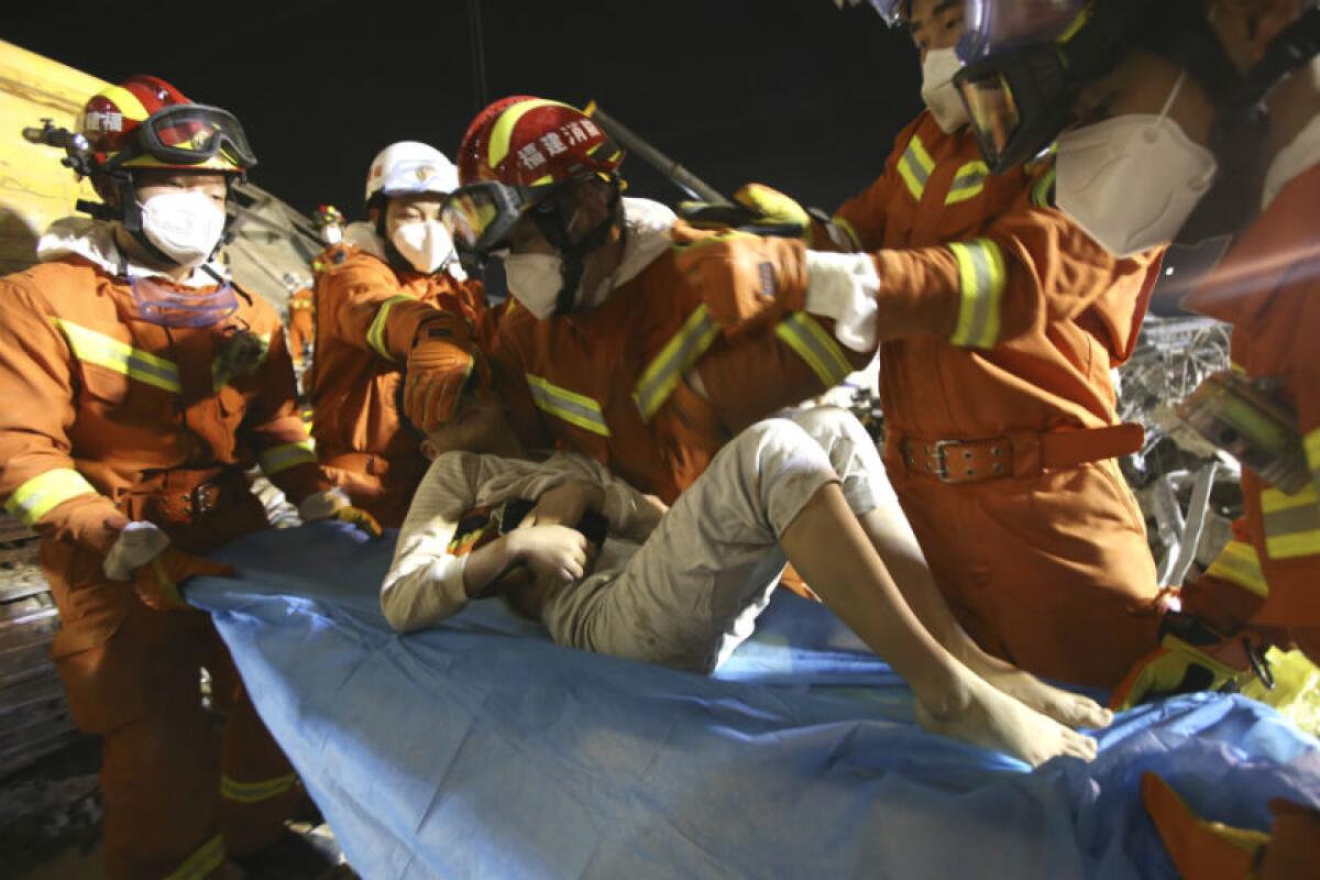 Rescuers treat a boy who was pulled from the rubble of a collapsed hotel in Quanzhou, China