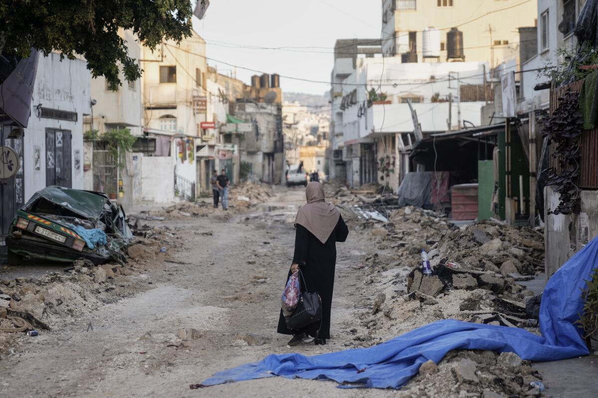 Woman walking amid rubble after fighting in the West Bank