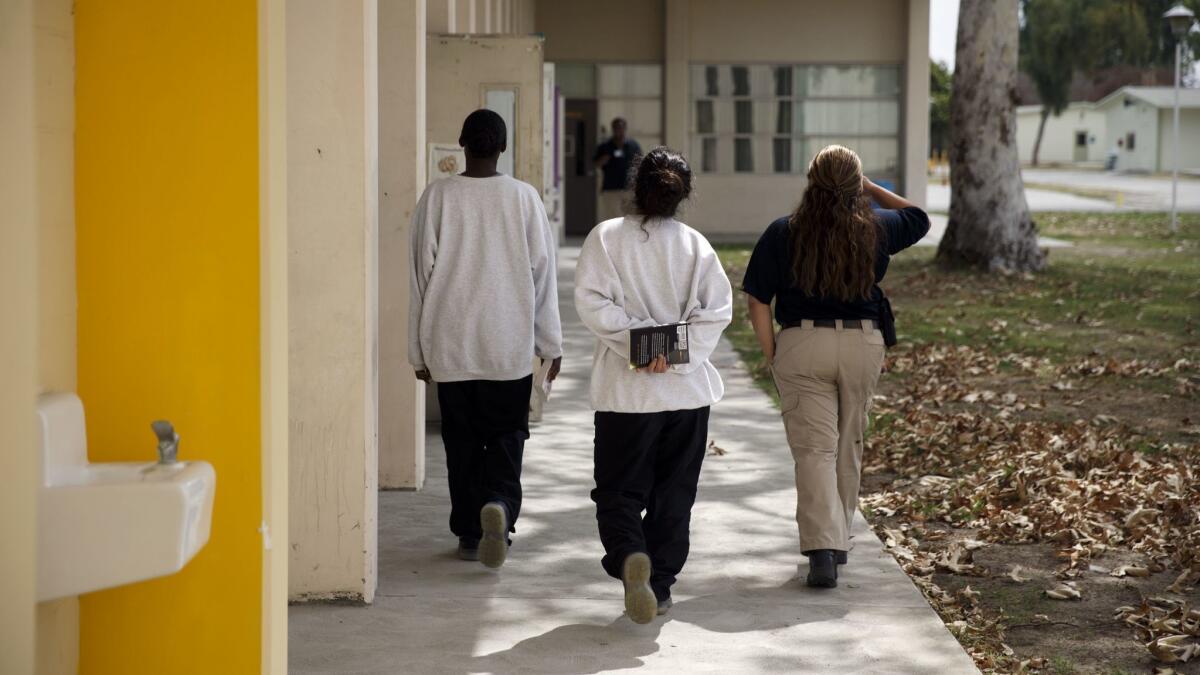Female minors are escorted by a probation officer at Los Padrinos Juvenile Hall in Downey, Calif. on Sept. 12.