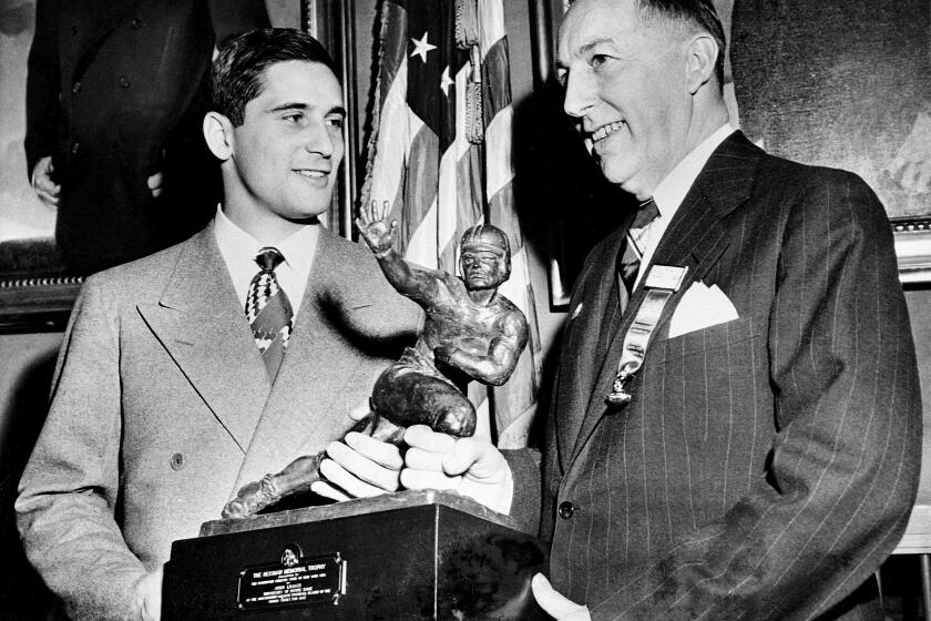 FILE - Notre Dame quarterback Johnny Lujack, left, recceives the Heisman Memorial Trophy from Wilbur Jurden, president of the Downtown Athletic Club in New York, Dec. 10, 1947. Lujack, the Heisman Trophy winner who led Notre Dame to three national championships in the 1940s, died in Florida on Tuesday, July 25, 2023, following a brief illness. He was 98. (AP Photo/Jacob Harris, File)