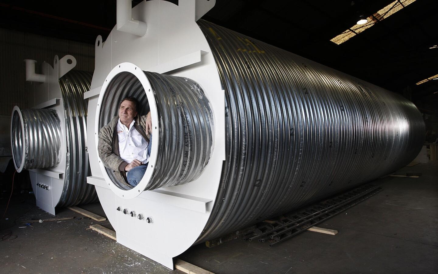 Ron Hubbard, owner of Atlas Survival Shelters, sits in the escape tunnel of a 33-foot corrugated metal underground shelter that his company assembles at his small plant in Montebello.