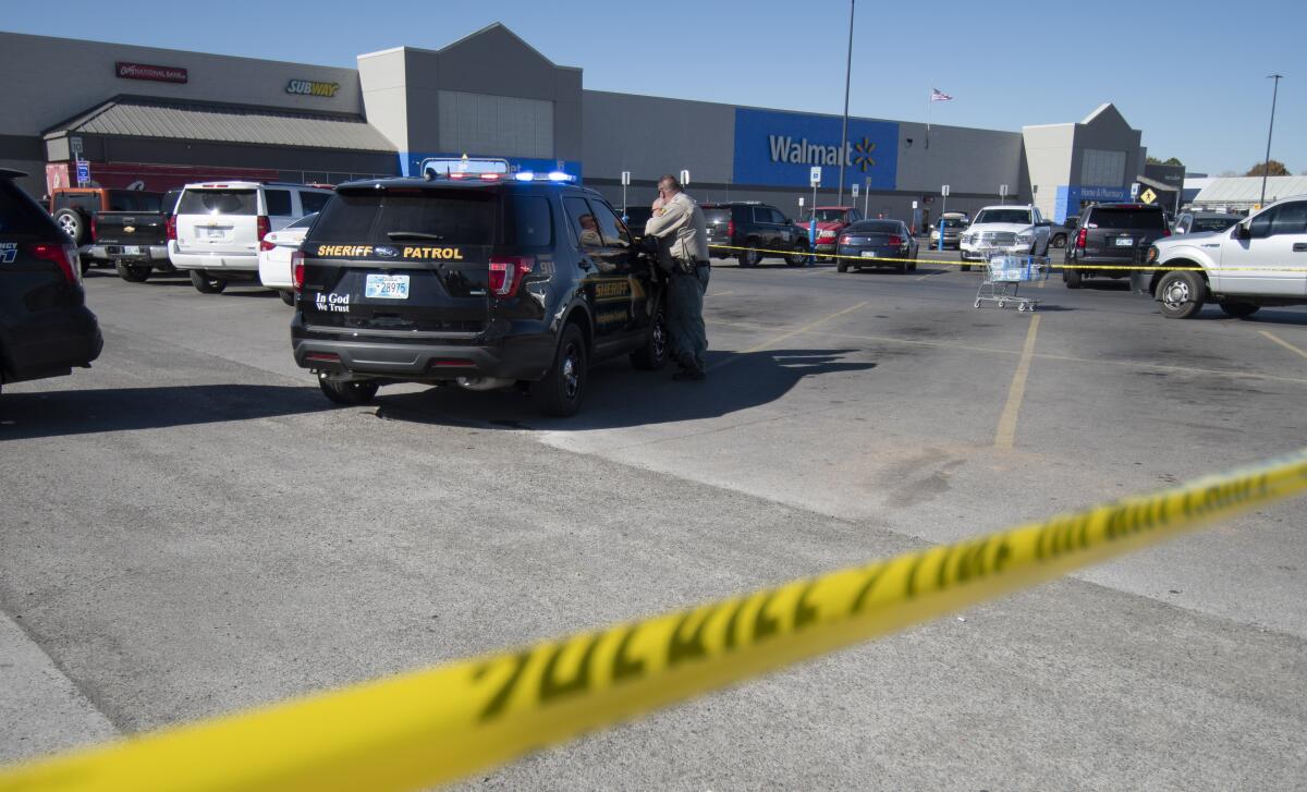 A police officer maintains a security line after a shooting in a Walmart parking lot in Duncan, Okl.