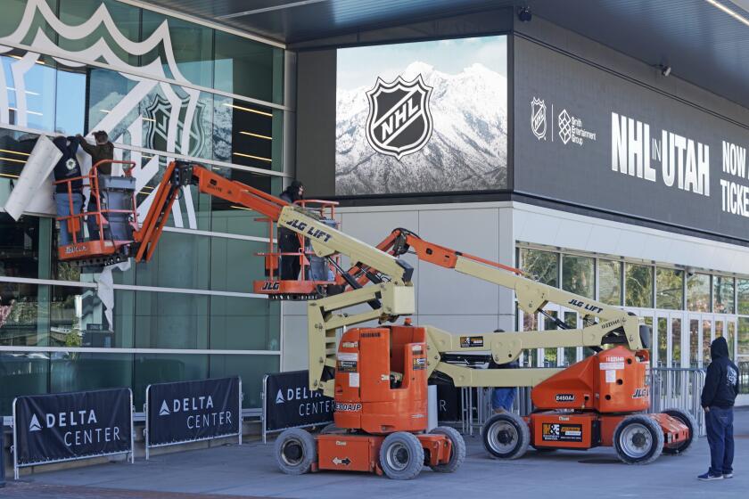 FILE - Workers put up signs celebrating the awarding of a new NHL team to Utah at the Delta Center Thursday, April 18, 2024, in Salt Lake City. It may look like an NHL team has just fallen into Salt Lake City's lap. But local organizers say the Arizona Coyotes' relocation to Utah is the product of a yearslong effort to beckon professional hockey and other elite sports to the capital city. (AP Photo/Rick Bowmer, File)