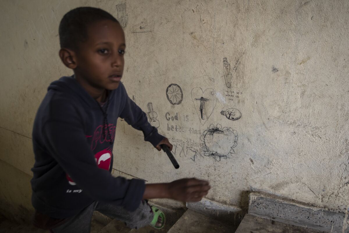 A displaced Tigrayan boy runs up stairs past graffiti reading "God is better than any thing" at the Hadnet General Secondary School which has become a makeshift home to thousands displaced by the conflict, in Mekele, in the Tigray region of northern Ethiopia Wednesday, May 5, 2021. The Tigray conflict has displaced more than 1 million people, the International Organization for Migration reported in April, and the numbers continue to rise. (AP Photo/Ben Curtis)