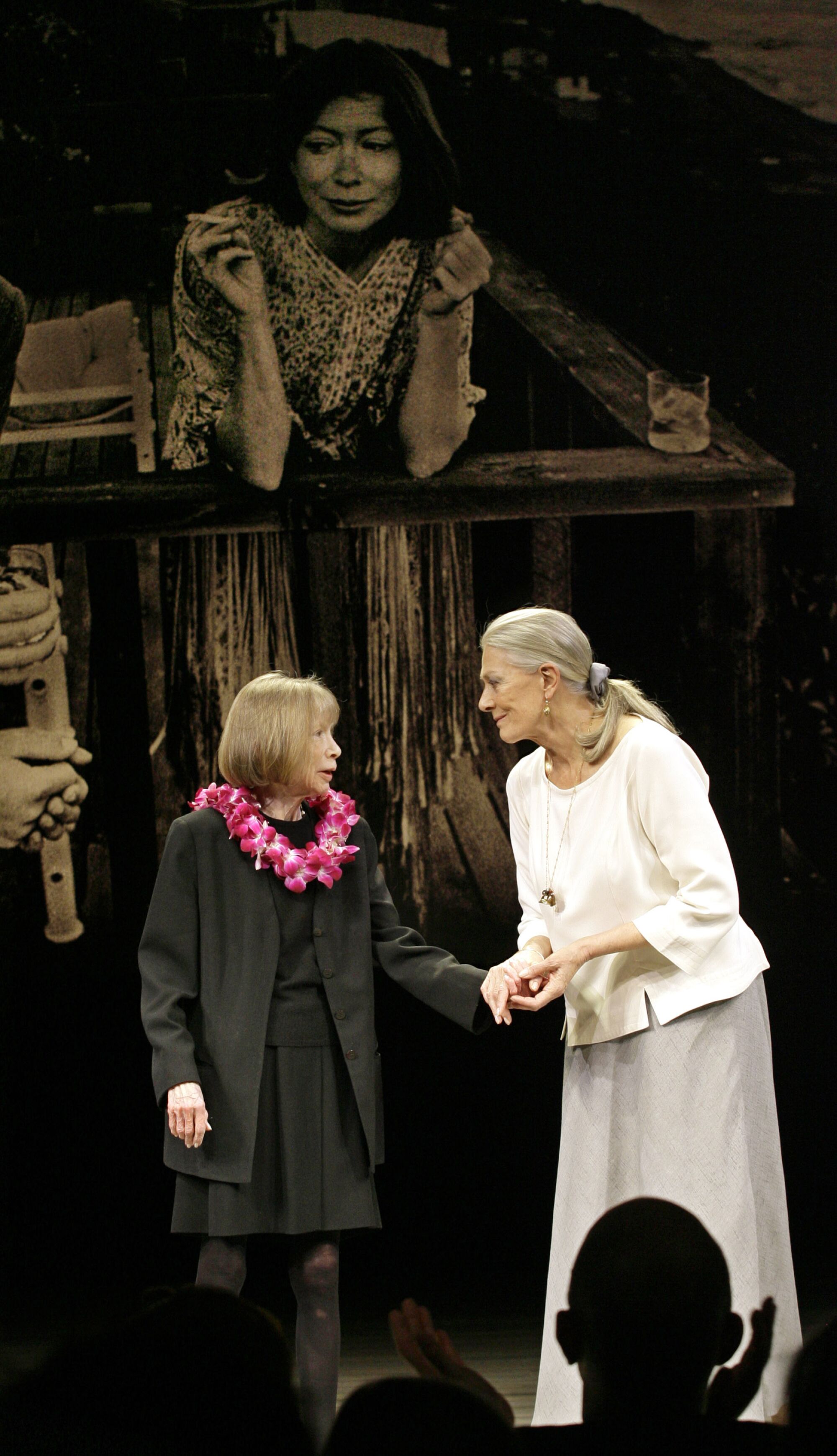 Joan Didion holds hands on stage with Vanessa Redgrave