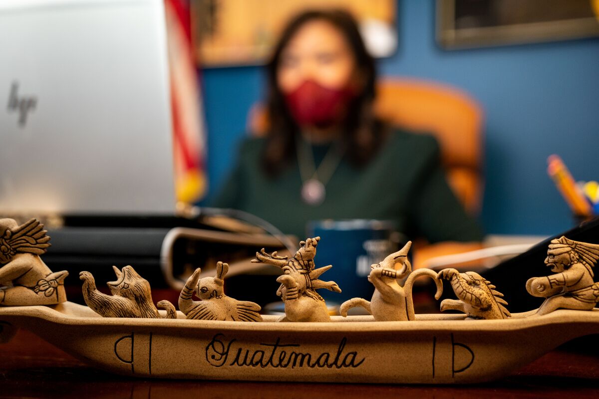 A carving from Guatemala of a boat carrying mythical Maya figures sits on Torres' desk.