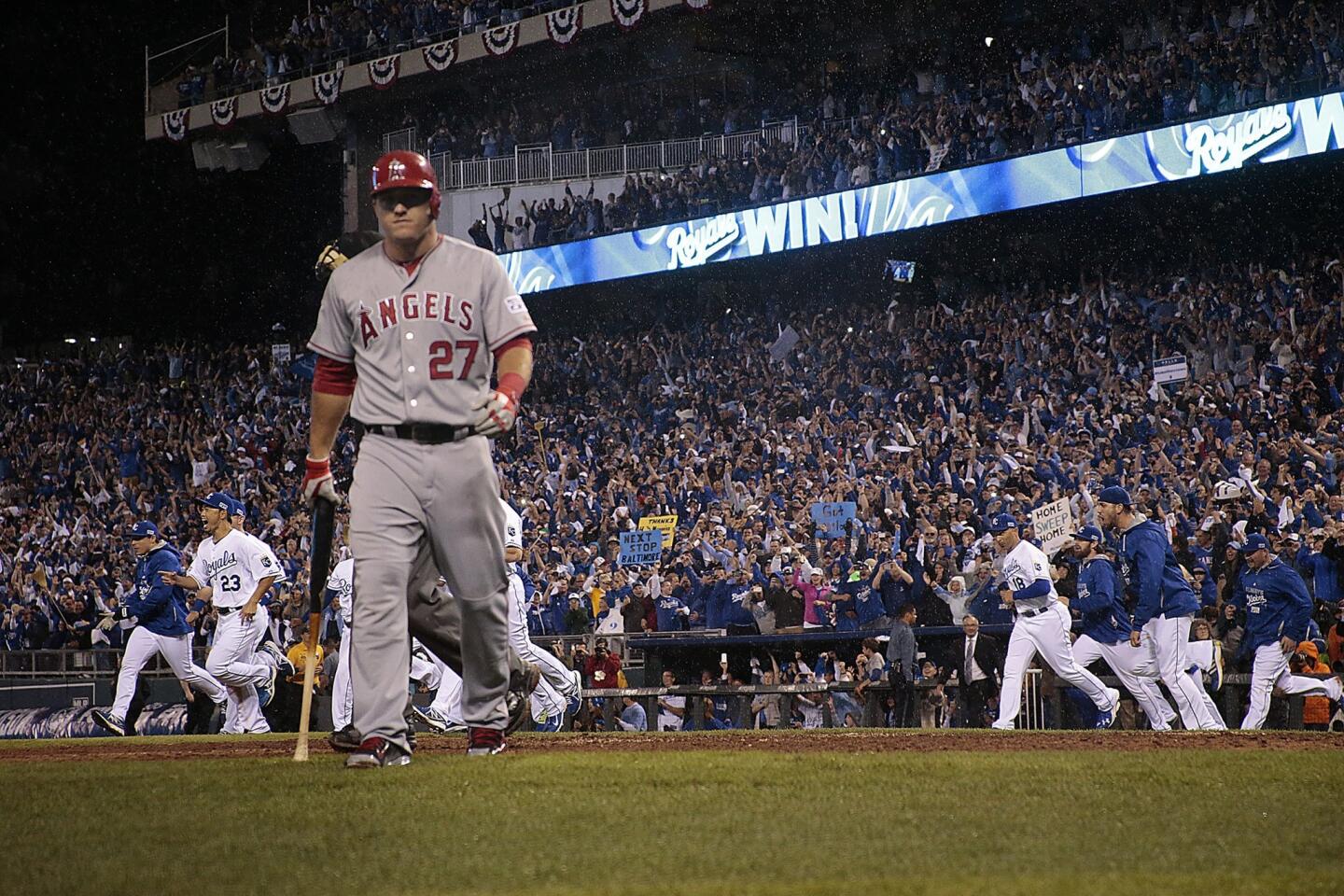Angels center fielder Mike Trout walks to the dugout as the Kansas City Royals celebrate their series-clinch victory in Game 3 of the ALDS on Sunday.