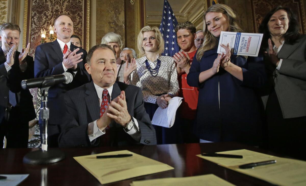 Utah Gov. Gary Herbert, left, claps during a ceremonial signing of a state resolution declaring pornography a public health crisis Tuesday in Salt Lake City.
