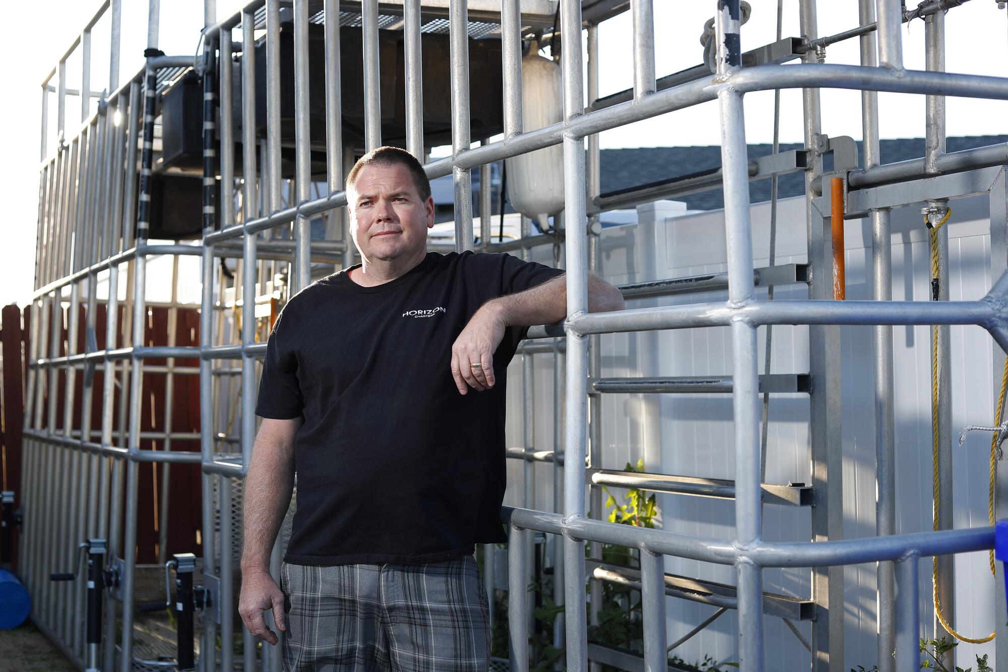 Spencer Salmon stands with shark-diving cages at his home