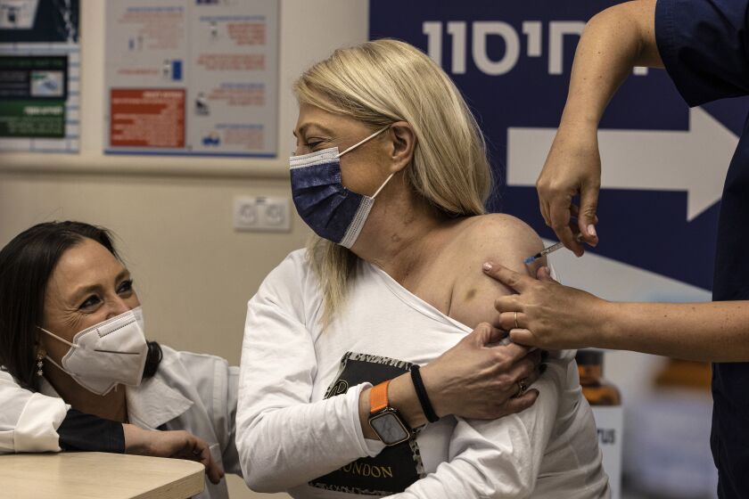Rinat Orion receives the fourth dose of the Pfizer-BioNTech COVID-19 vaccine at the Sheba Medical Center in Ramat Gan, Israel, Friday, Dec. 31, 2021. (AP Photo/Tsafrir Abayov)