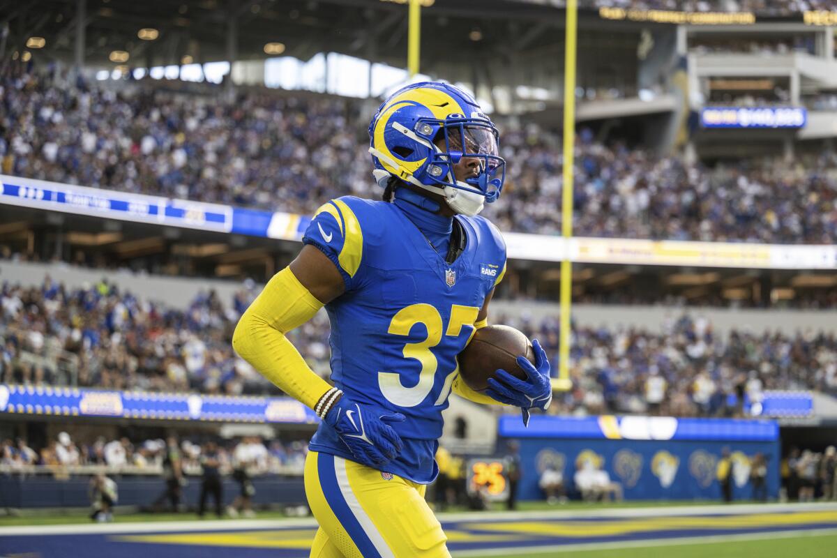 Rams safety Quentin Lake (37) jogs back to the bench with the football after recovering a fumble against the Cardinals.