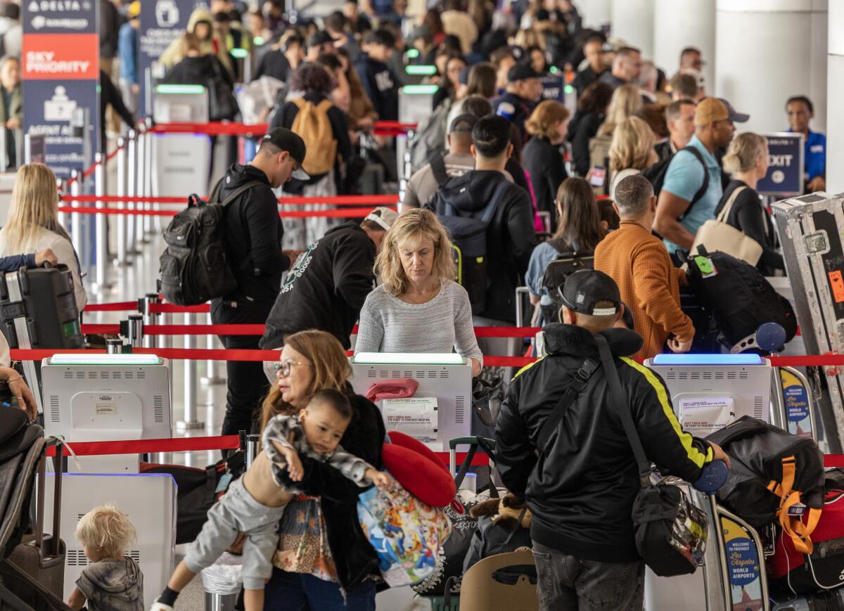 Travelers get boarding passes and check in baggage at Los Angeles International Airport.