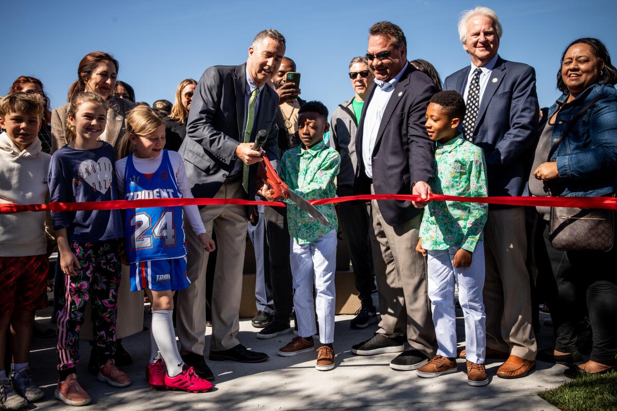Children help cut a ribbon at a ceremony