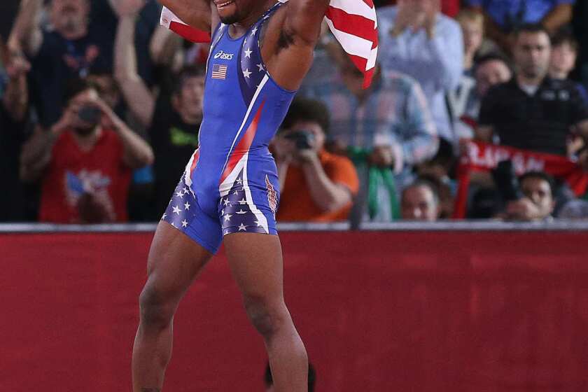 Jordan Burroughs of the United States jumps on the victory podium and celebrates his defeat of Iran's Sadegh Saeed Goudarzi to win the men's wrestling gold medal.