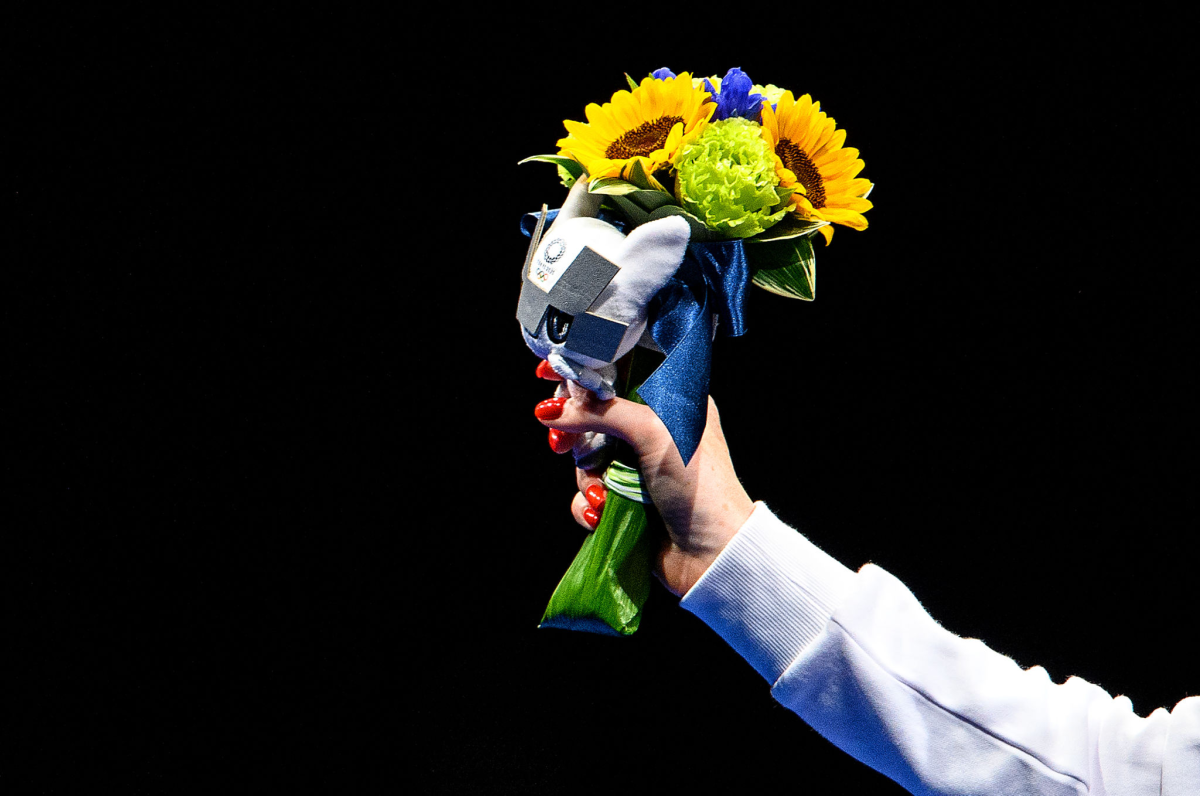 Women's fencing silver medalist Inna Deriglazova of Team ROC poses with flowers in her hand.