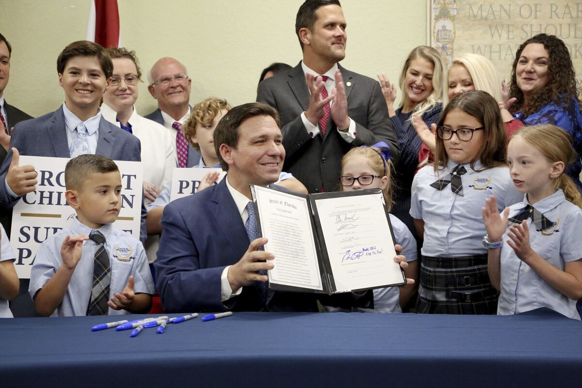 A man displays the signed Parental Rights in Education law in front of adults and children