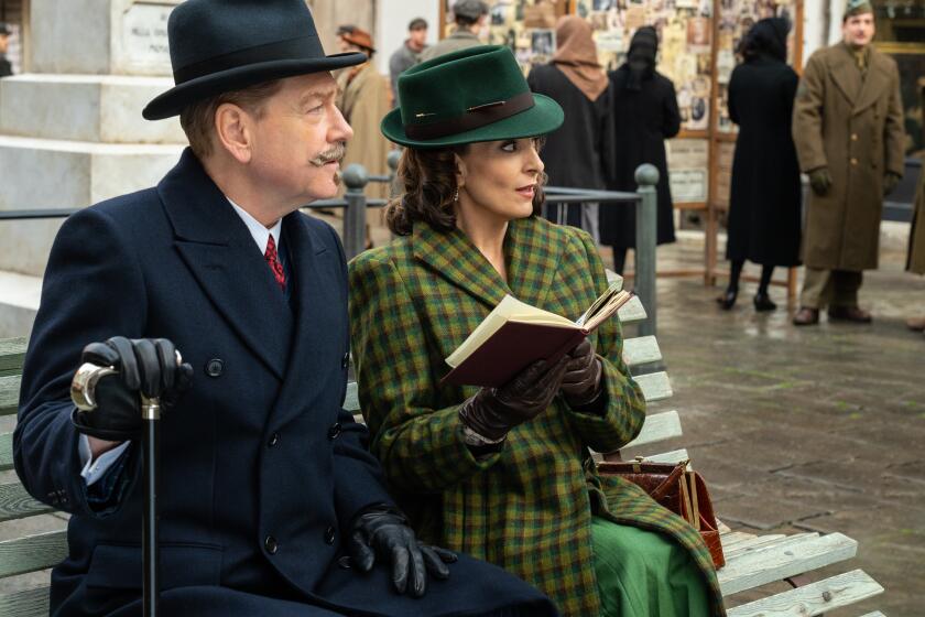 A detective and a novelist sit on a bench in 1947 Venice in a scene from the movie "A Haunting in Venice."