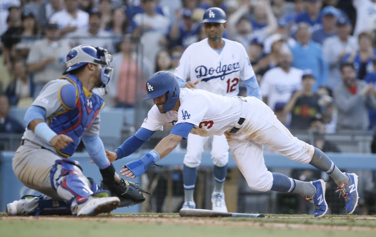 Dodgers third-base coach Dino Ebel, background, decided to wave Chris Taylor home. Taylor slides away from the tag by Chicago Cubs catcher Willson Contreras.