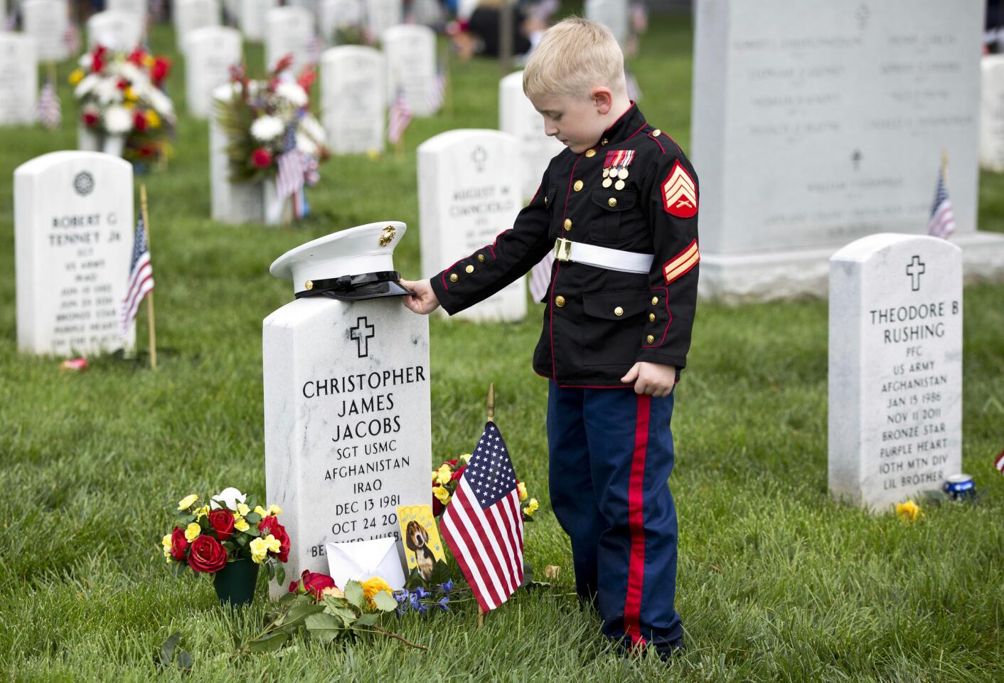 Christian Jacobs, 5, of Hertford, N.C., dressed as a Marine, stands at his father's gravestone on Memorial Day in Section 60 at Arlington National Cemetery in Arlington, Va., Monday, May 30, 2016. Christian's father Marine Sgt. Christopher James Jacobs died in a training accident in 2011. (AP Photo/Carolyn Kaster)