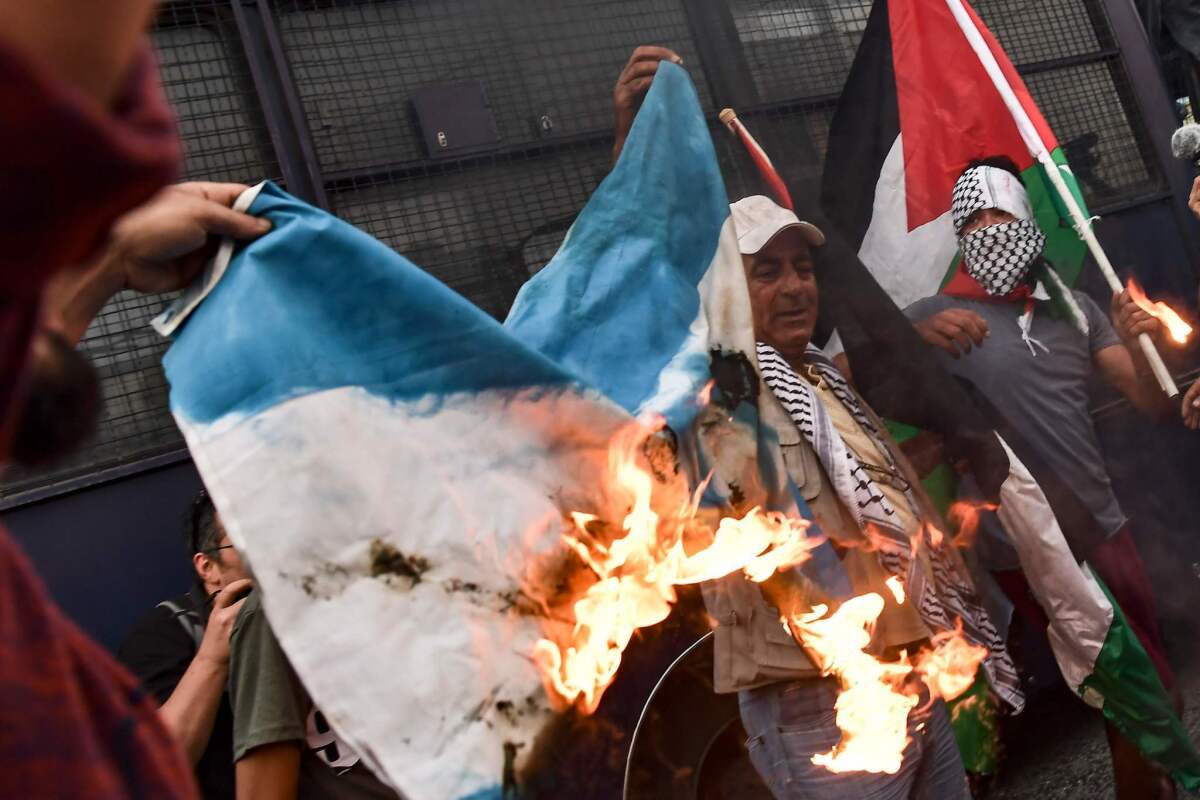 Manifestantes queman una bandera de Israel y gritan consignas en una protesta que denuncia el derramamiento de sangre en Gaza.