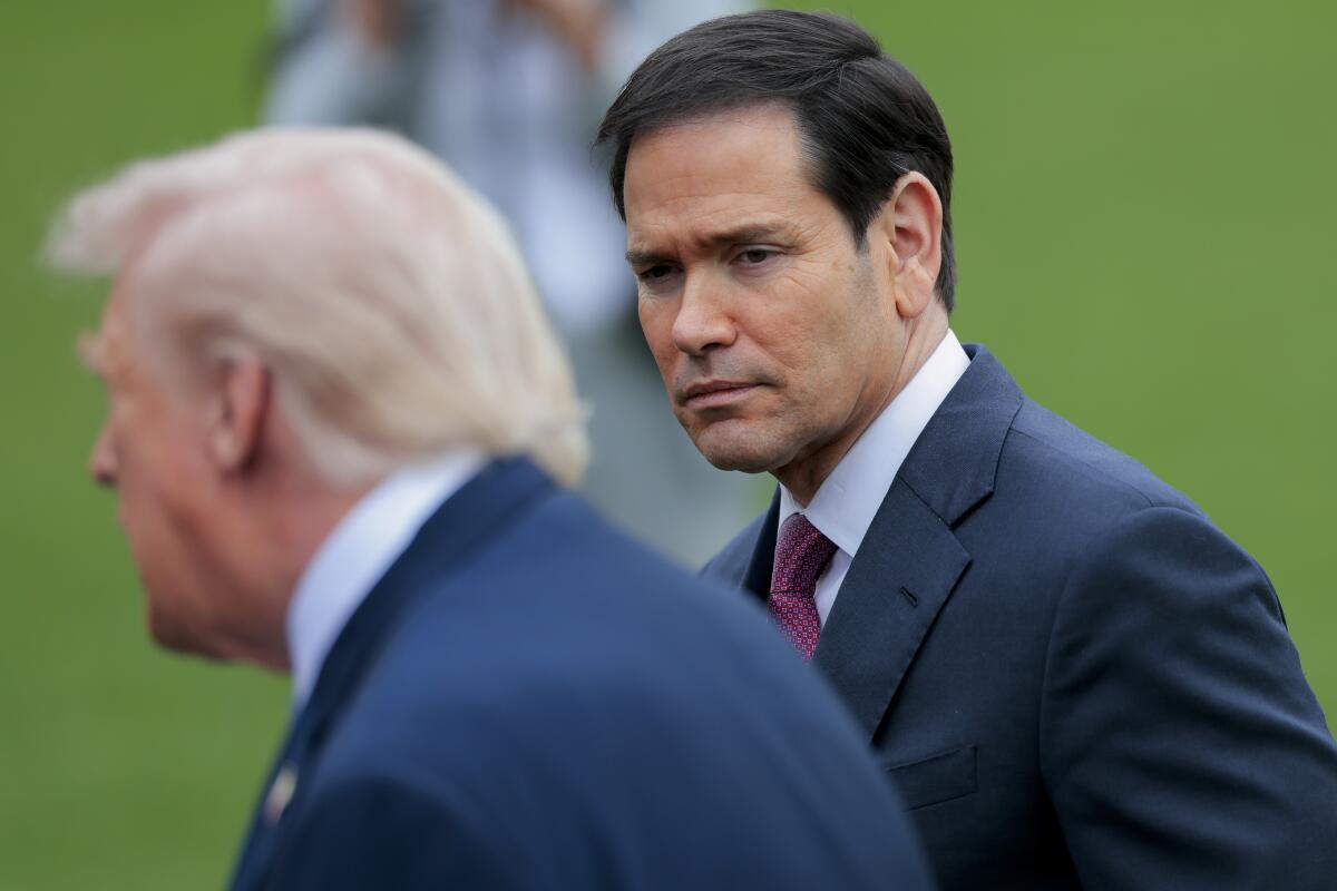 U.S. Secretary of State Marco Rubio looks on as President Trump stops to speak to reporters.