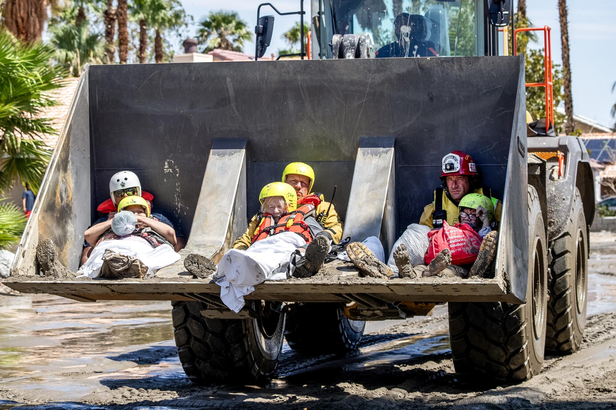 Residents from a senior living facility are held by firefighters in a front loader while being 